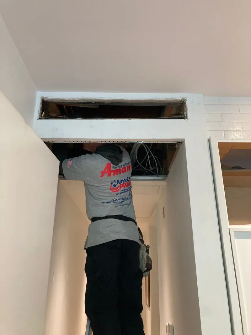 HVAC technician working inside a ceiling cavity on a Brooklyn diagnostic call
