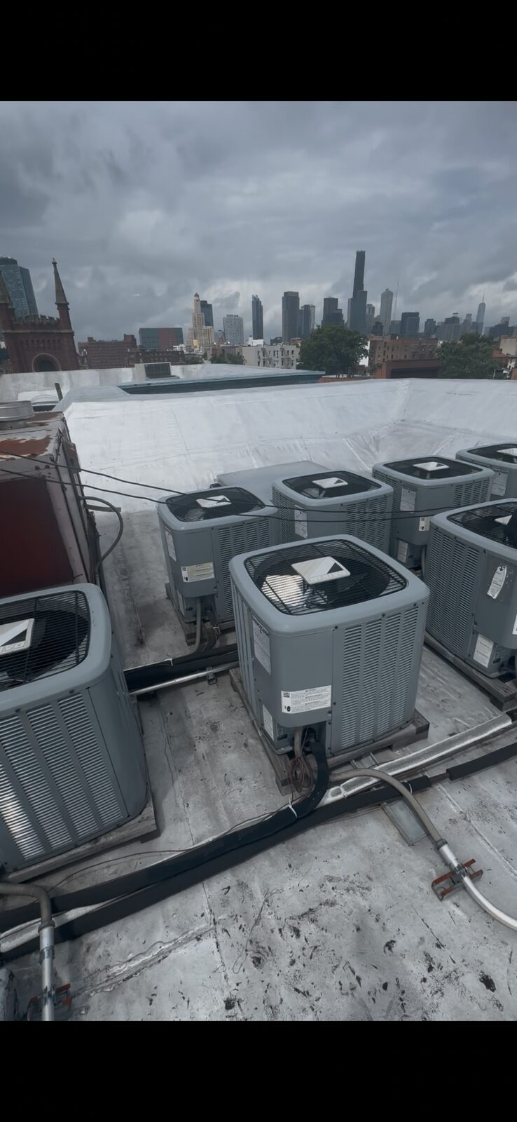 Multiple Daikin condensers installed clean on a Brooklyn rooftop with the skyline behind