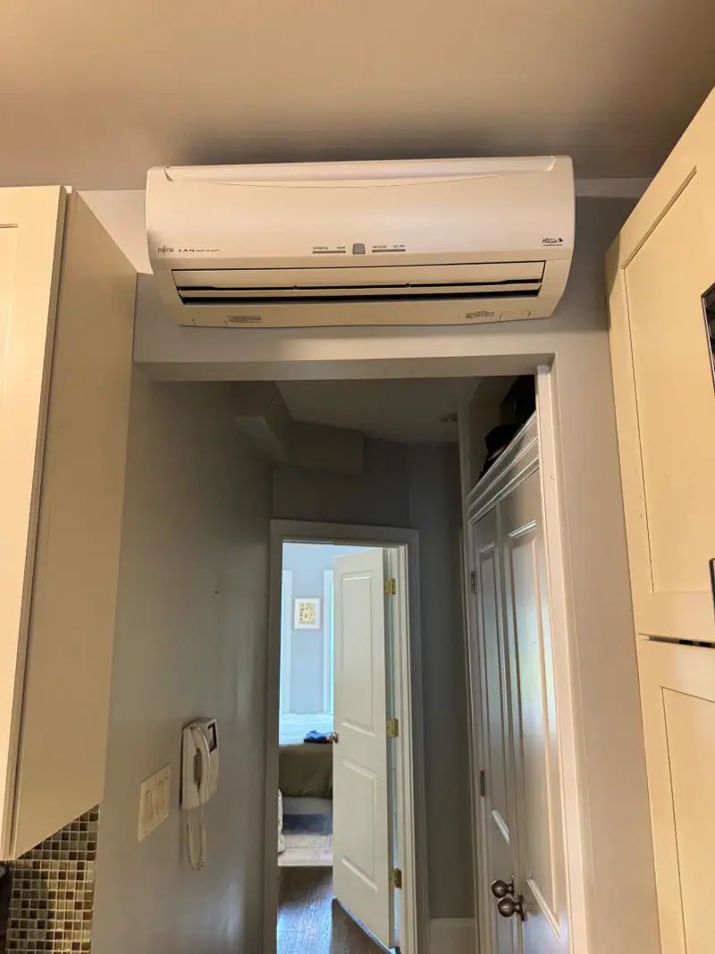 Clean Fujitsu mini-split wall head mounted above a doorway after a deep cleaning
