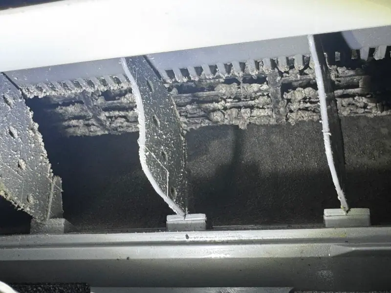 Mini-split blower wheel caked with grey dust and biofilm before cleaning