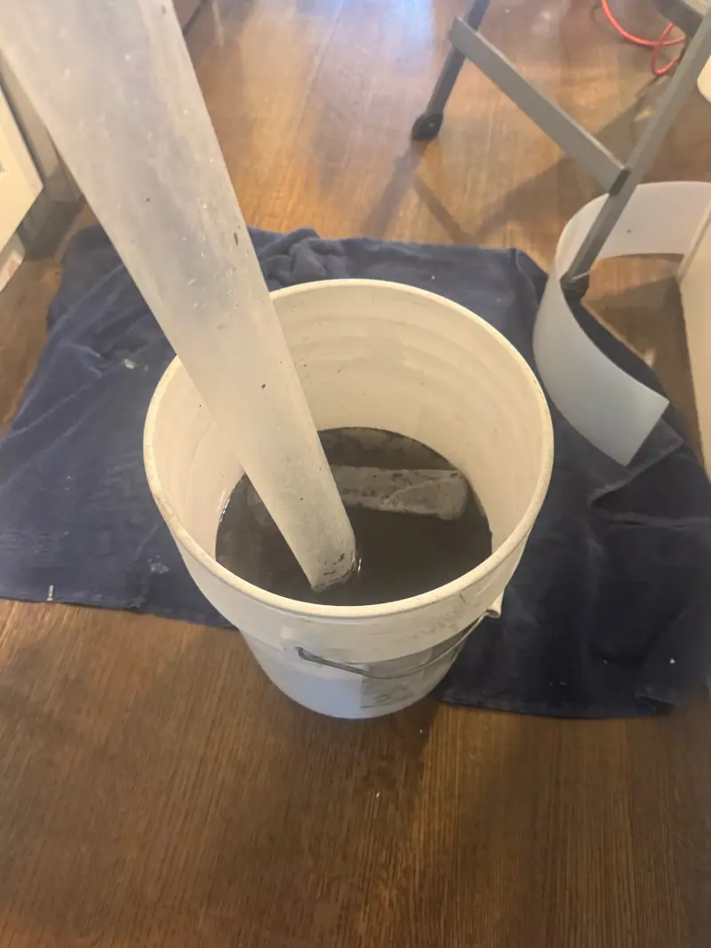 Bucket of dark runoff water drained from a mini-split head during a deep cleaning