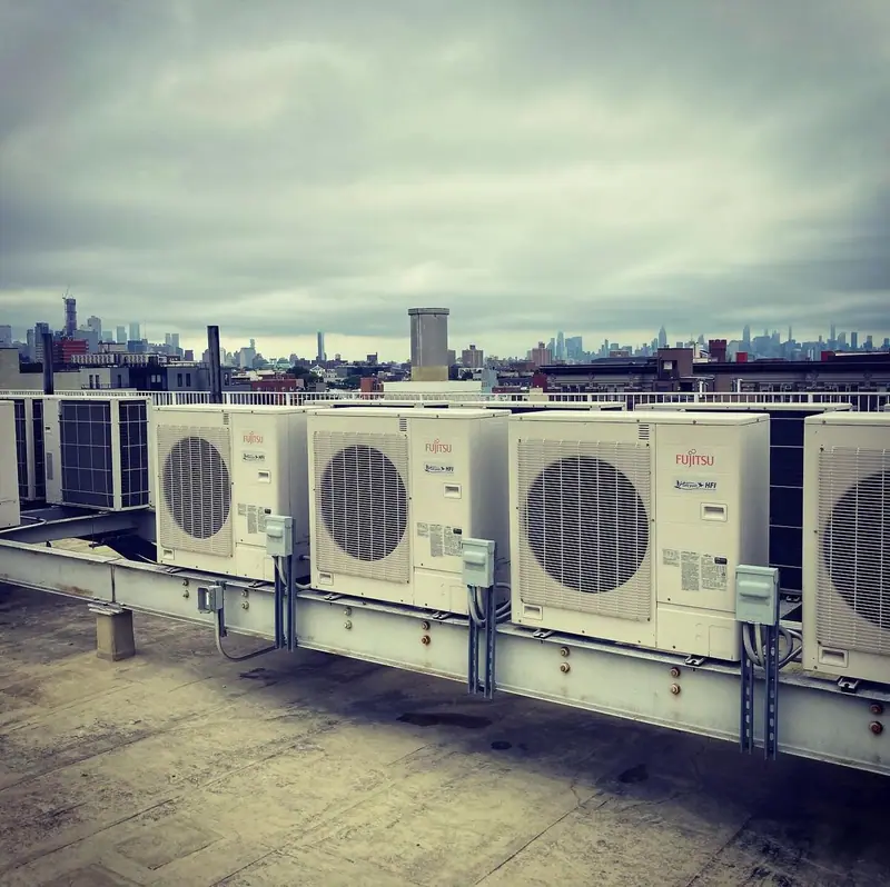 Fujitsu Halcyon condensers on a rooftop rail with the Manhattan skyline behind