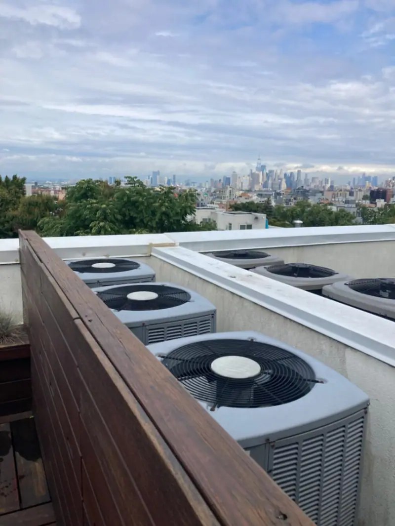 Brooklyn rooftop HVAC install — row of condensers overlooking Manhattan skyline