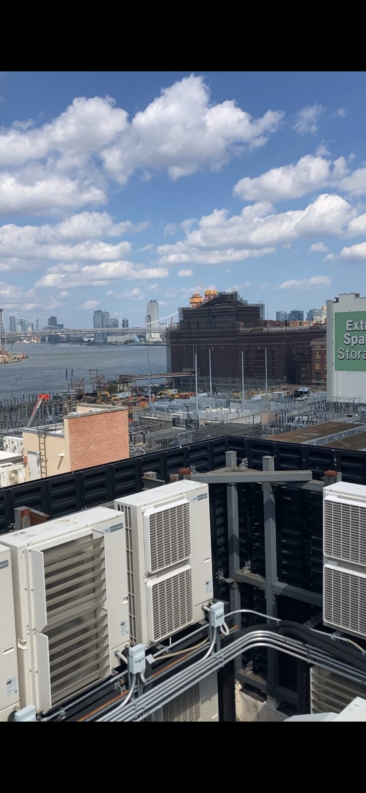 Bank of Fujitsu mini split condensers on a Brooklyn rooftop overlooking the East River