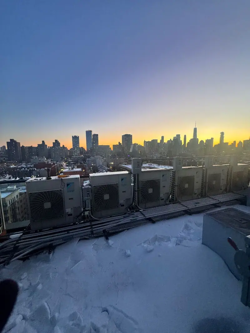 Daikin condensers on a snowy Brooklyn rooftop at sunset with the Manhattan skyline